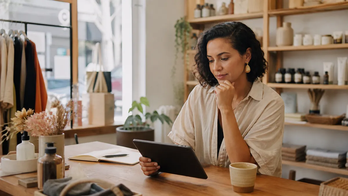 Shopify retailer planning a location-based marketing campaign on a tablet at a boutique desk